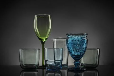 Set of different colorful empty glasses on table against grey background Stock Photos