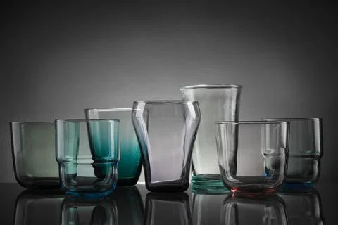 Set of different colorful empty glasses on table against grey background Stock Photos