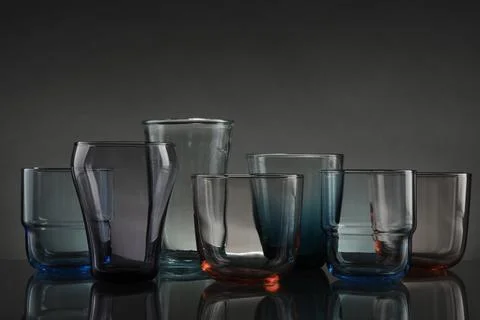 Set of different colorful empty glasses on table against grey background Stock Photos