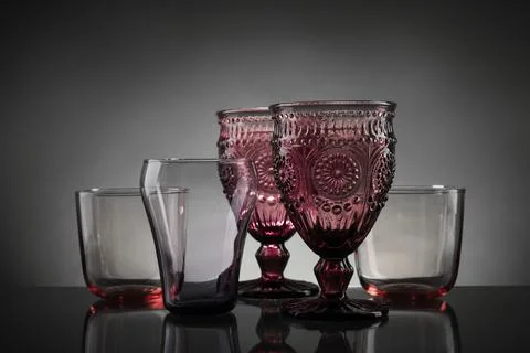 Set of different colorful empty glasses on table against grey background Stock Photos