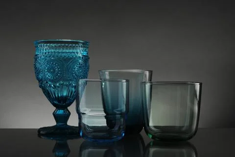 Set of different colorful empty glasses on table against grey background Stock Photos