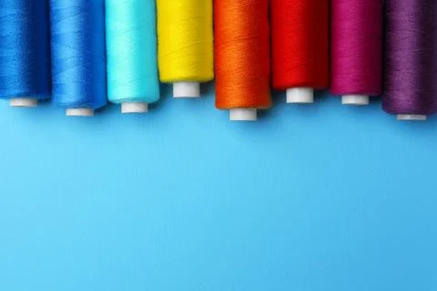 Set of different colorful sewing threads on light blue background, flat lay.. Stock Photos