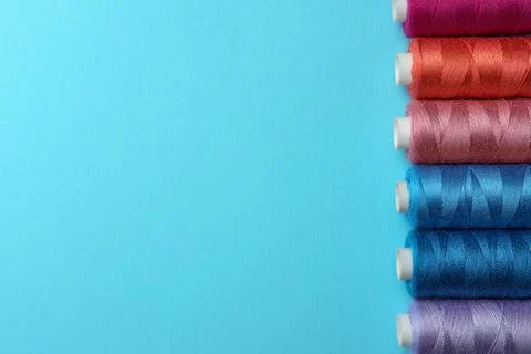 Set of different colorful sewing threads on light blue background, flat lay.. Stock Photos
