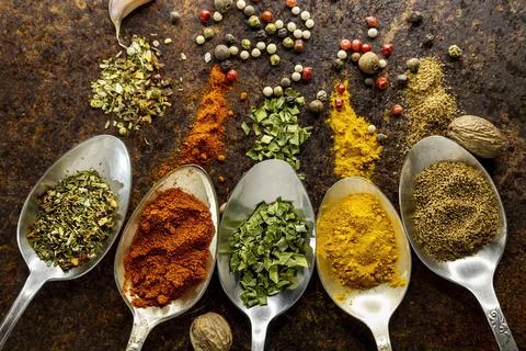 Set of different culinary spices scattered in old metal spoons on a rusty Stock Photos