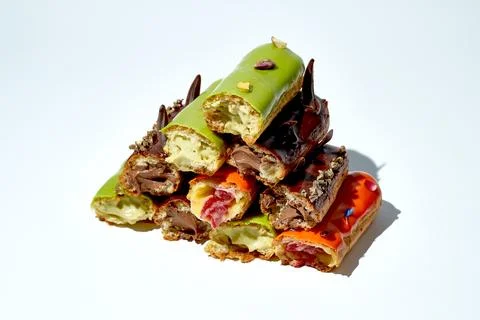 Set of different eclairs with different flavors cut in half. White background Stock Photos