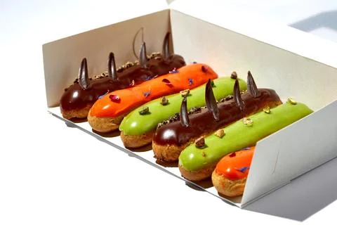 A set of different eclairs with different flavors in a packaging box. White.. Stock Photos