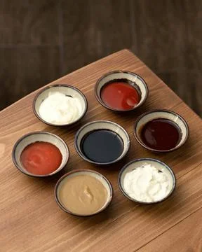 Set of different multi-colored sauces in crockery on wooden table. Variety of Stock Photos