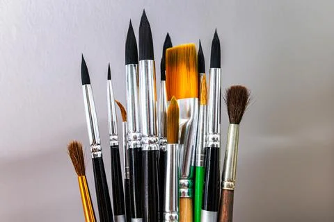 A set of different paint brushes isolated against a wall background. Layout Stock Photos