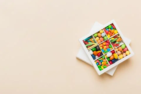 Set of different sweet candy in a paper box with a satin ribbon on a colore.. Stock Photos