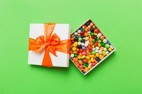 Set of different sweet candy in a paper box with a satin ribbon on a colore.. Stock Photos