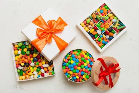 Set of different sweet candy in a paper box with a satin ribbon on a colore.. Stock Photos