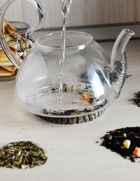 A set of different types tea next to the kettle filled with hot brewed tea on Stock Photos