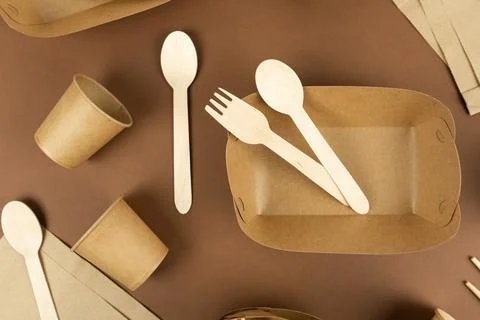 A set of disposable tableware and wood cutlery on brown background. Foto stock