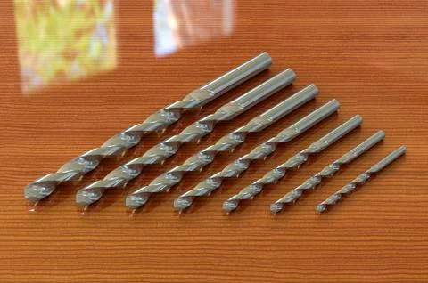 Set of drill bits on the wooden table. 3D rendering Ilustración de archivo