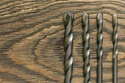 Set of drill bits on a wooden table, close up Stock Photos