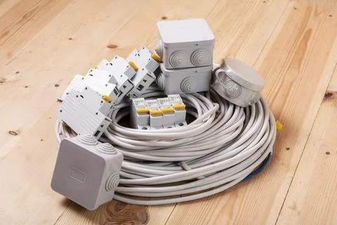 Set of electric cables, circuit breakers, and junction boxes on wooden floor Stock Photos