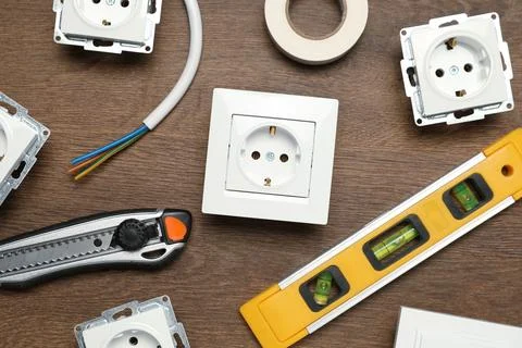 Set of electrician's tools and power sockets on wooden table, flat lay Stock Photos