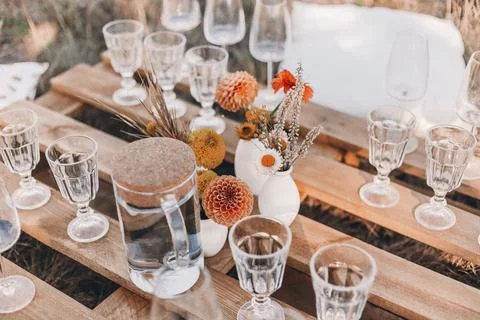 Set of elegant glassware placed on plank wooden table with floral arrangement on 스톡 사진