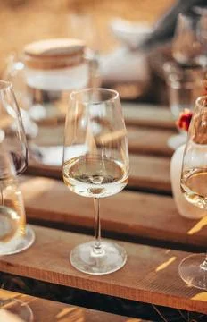 Set of elegant glassware placed on plank wooden table with floral arrangement on Stock Photos