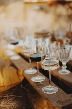 Set of elegant glassware placed on plank wooden table with floral arrangement on Stock Photos