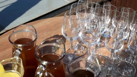 A set of empty glasses displayed in rows and a decanters of cool lemonade. Stock Footage 156209086