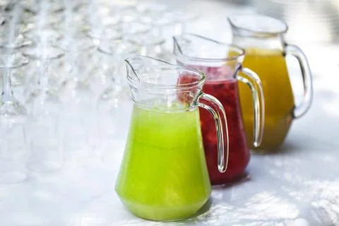 A set of empty glasses displayed in rows. Decanters with colored lemonade 스톡 사진