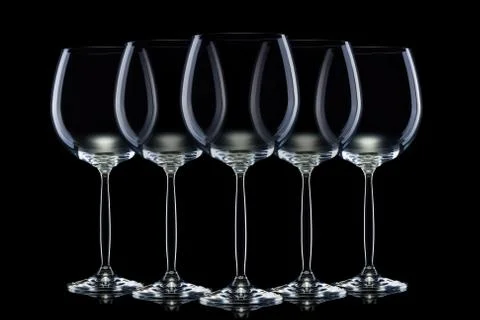 Set of empty glasses for red wine in a row isolated on black background. Stock Photos