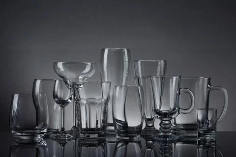Set of empty glasses on table against grey background Stock Photos