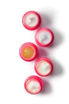 Set of five red jars with moisturizers for the face in a row, top view. The Stock Photos