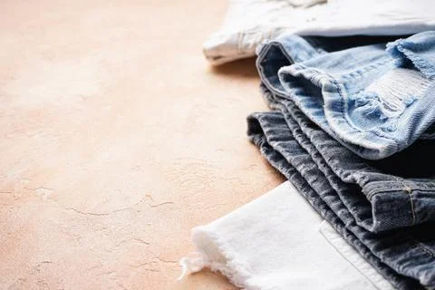 Set of folded jeans on a beige background, space for text. Close-up Stock Photos