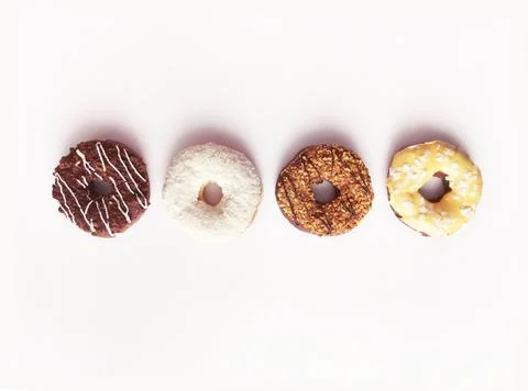 Set of four multi-colored donuts in a row on a white background. pink toning. Stock Photos