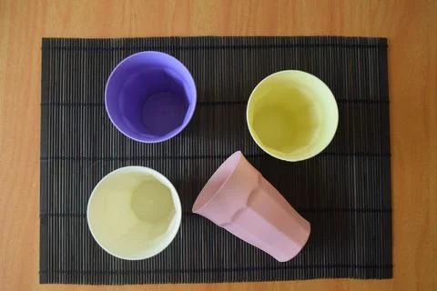 Set of Four Pastel Plastic Drinking Cups on a Japanese Bamboo Mat Stock Photos