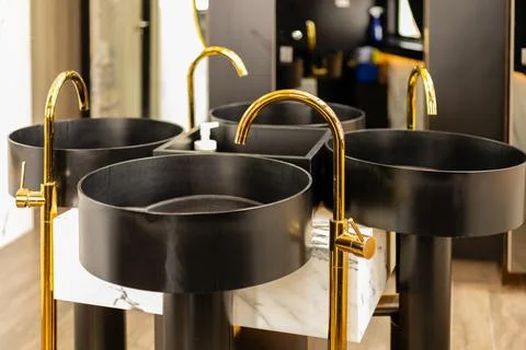 A set of four round black sinks sits on a marble base in a contemporary bathr Stock Photos