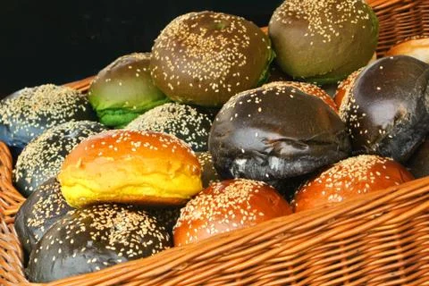 A set of fresh burger buns of different color with sesame seeds in the basket Stock Photos