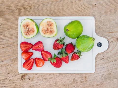 A set of fresh fruit on a white ceramic cutting board with a wooden backgroun Stock Photos