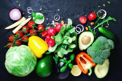 Set of fresh vegetables on a black background. Aromatic herbs, onion, avocado Stock Photos