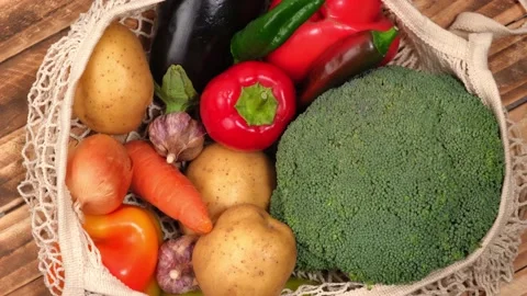 Set of fresh vegetables in string bag rotates on wooden background. top view. 4k Video stock 217384457