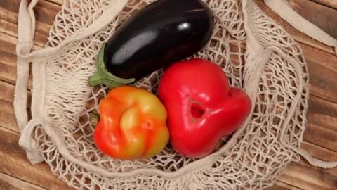 Set of fresh vegetables in string bag on a wooden background. closeup rotation. Stock Footage 252830758