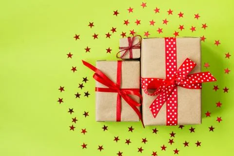 Set of gift boxes wrapped in craft paper with red ribbons on a green background Stock Photos