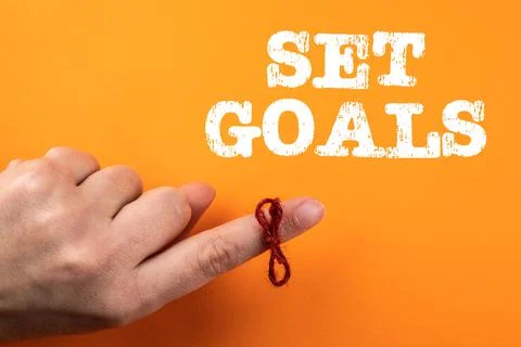 Set Goals. String tired around finger on orange background Stock Photos