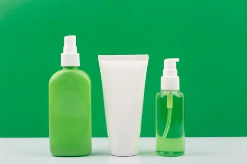 Set of green and white cosmetic bottles against green background. Stock Photos