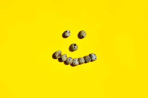 Set of group quail eggs form a smile face on a yellow background. Stock Photos