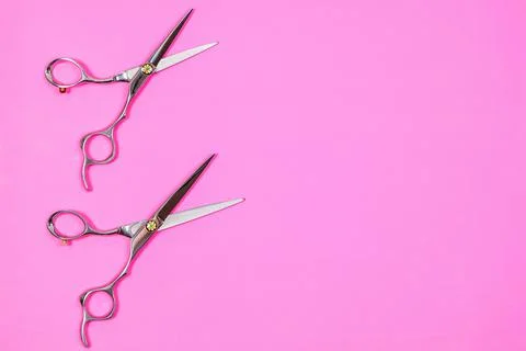 A set of hairdressing tools of two scissors on a pink background. Stock Photos