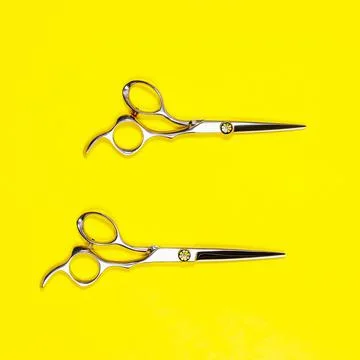 A set of hairdressing tools from two scissors on a yellow background. Stock Photos