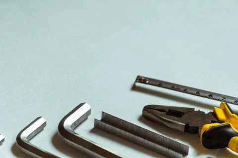 A set of hex keys next to a pliers and a tape measure on a white background. Stock Photos