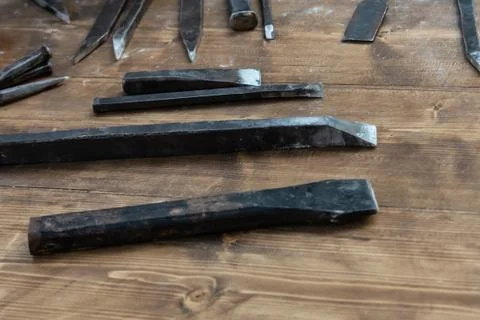Set of iron chisels sharp mason tool lies on a wooden table to create a patte Stock Photos