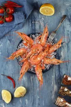 Set of king prawns in plate with fork and vegetables around. Seafood. Stock Photos