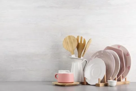 Set of kitchenware on table near light wall, space for text. Modern interior  Stock Photos