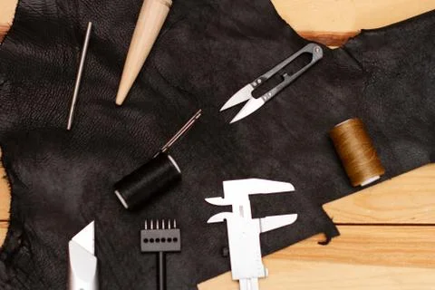 Set of leather work tools on black leather Stock Photos