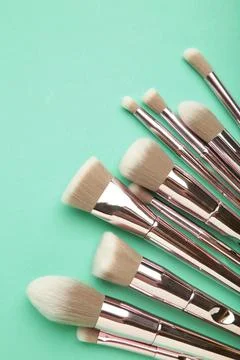Set of makeup brushes on mint background. Top view. Space for text Stock Photos